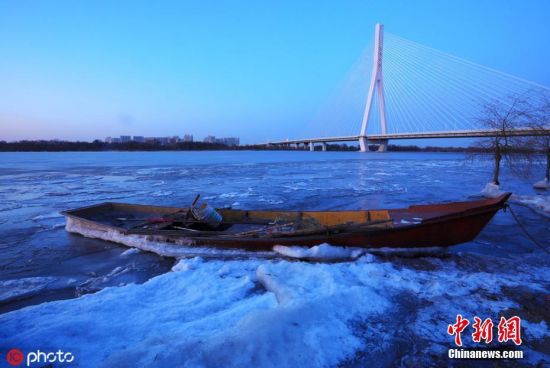 11月16日，黑龙江省哈尔滨市，进入流冰期的松花江，岸边堆满晶莹冰块，在松浦大桥、滨洲铁路桥的灯光映射下，一江璀璨如画。张澍