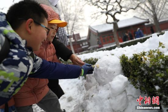 11月30日，小朋友在北京景山公园内堆雪人。29日，北京迎来2019年冬季初雪。中新社记者
