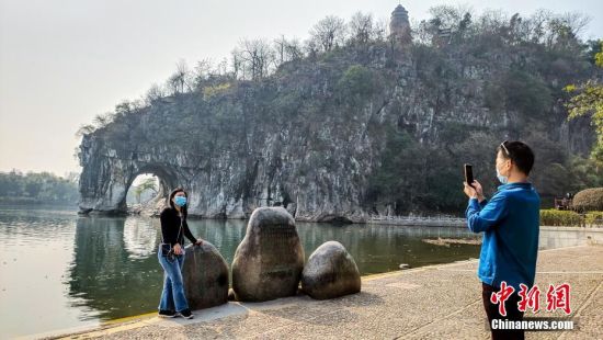 2月26日，广西桂林市象山景区正式对外恢复开放。这是广西桂林市21日宣布该市82个A级旅游景区向国内外疫情防控低风险地区游客有序开放的首个景区。图为来自广东的游客在象鼻山前拍照留念。