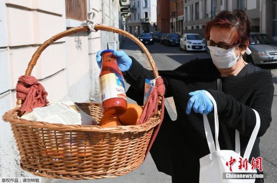 当地时间4月9日，新冠肺炎疫情期间，意大利米兰，一名路过“捐赠筐”的女士往篮筐中放入杂货。