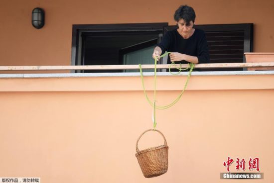 当地时间4月9日，新冠肺炎疫情期间，意大利米兰，一名女士从阳台放下篮子，人们可以捐赠食物或免费享用篮子里的食物。