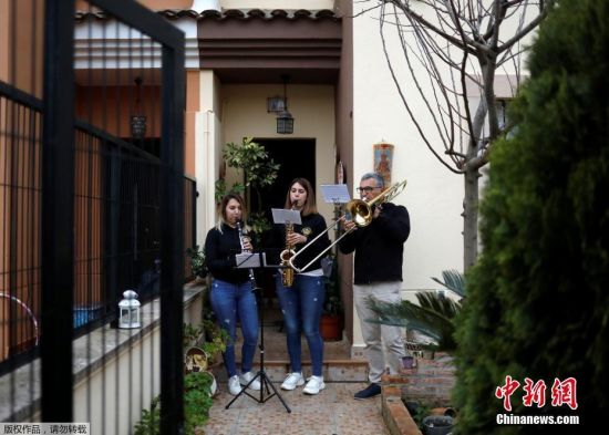 当地时间4月9日，西班牙南部隆达，新冠状病毒病期间，54岁的埃勒特罗蒂奥·莫亚和他的女儿25岁的帕洛玛、22岁的玛塔，在他们的家门口演奏乐曲庆祝复活节。