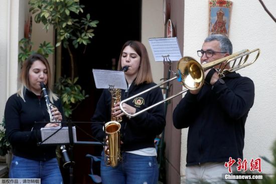 当地时间4月9日，西班牙南部隆达，新冠状病毒病期间，54岁的埃勒特罗蒂奥·莫亚和他的女儿25岁的帕洛玛、22岁的玛塔，在他们的家门口演奏乐曲庆祝复活节。
